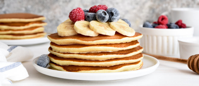 Stack of protein pancakes with banana and berries